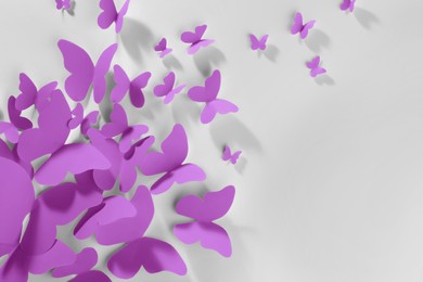 Bright violet paper butterflies on white wall