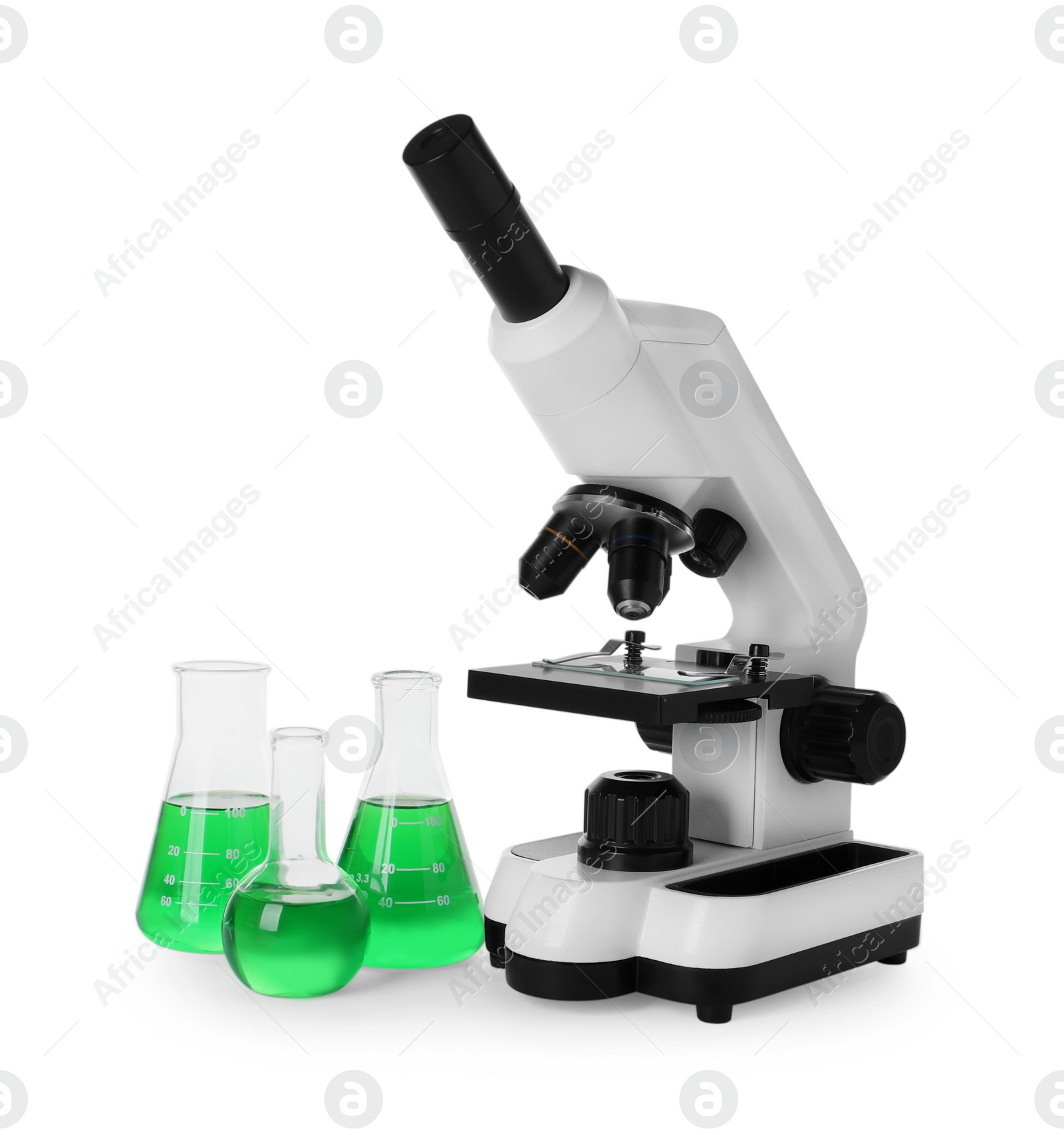 Photo of Laboratory glassware with green liquid and microscope isolated on white