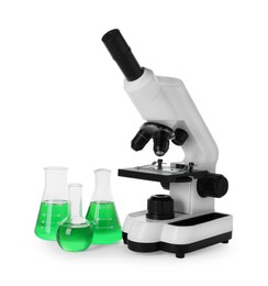 Laboratory glassware with green liquid and microscope isolated on white