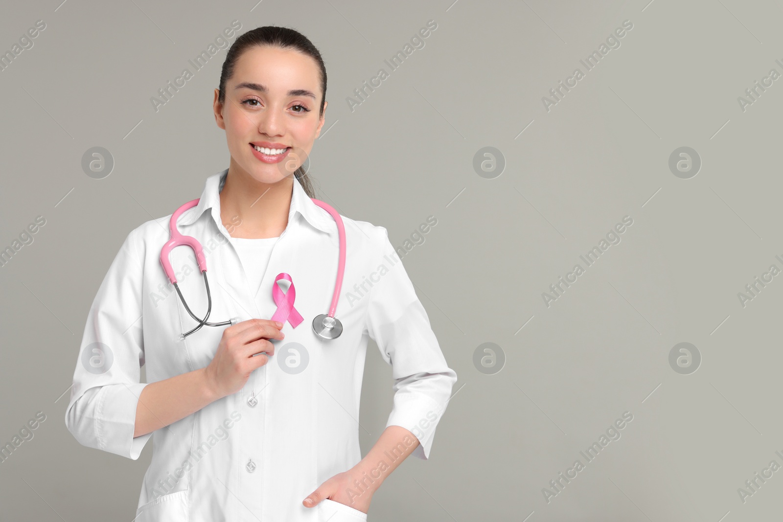 Photo of Mammologist with pink ribbon on gray background, space for text. Breast cancer awareness