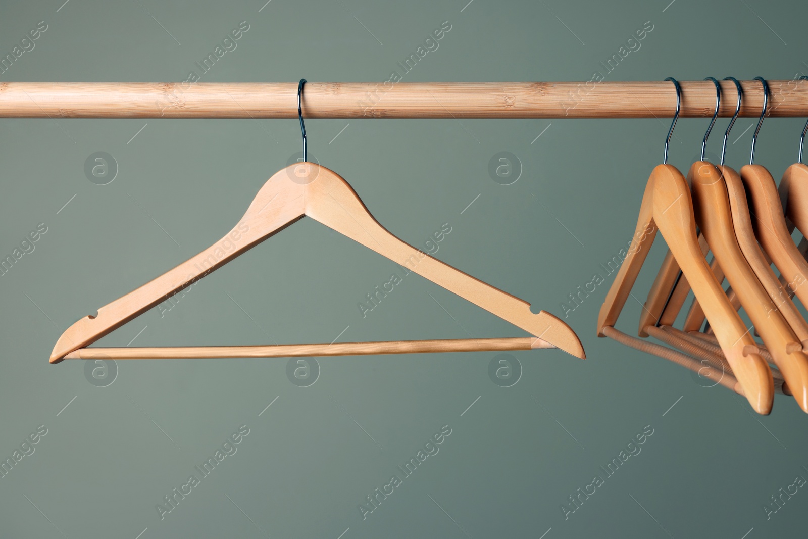 Photo of Clothes hangers on wooden rail against beige background