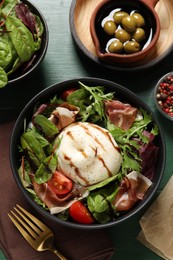 Photo of Delicious burrata salad served on green wooden table, flat lay