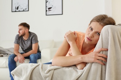 Photo of Young couple ignoring each other after argument in living room. Relationship problems