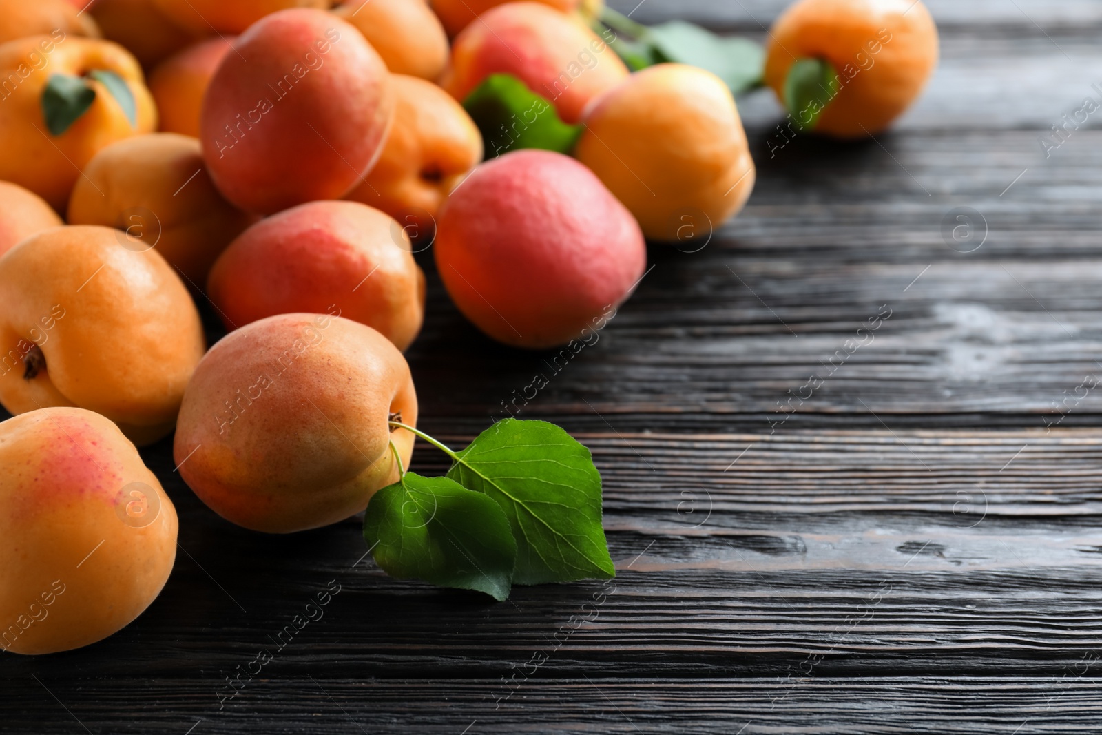 Photo of Many fresh ripe apricots on black wooden table. Space for text