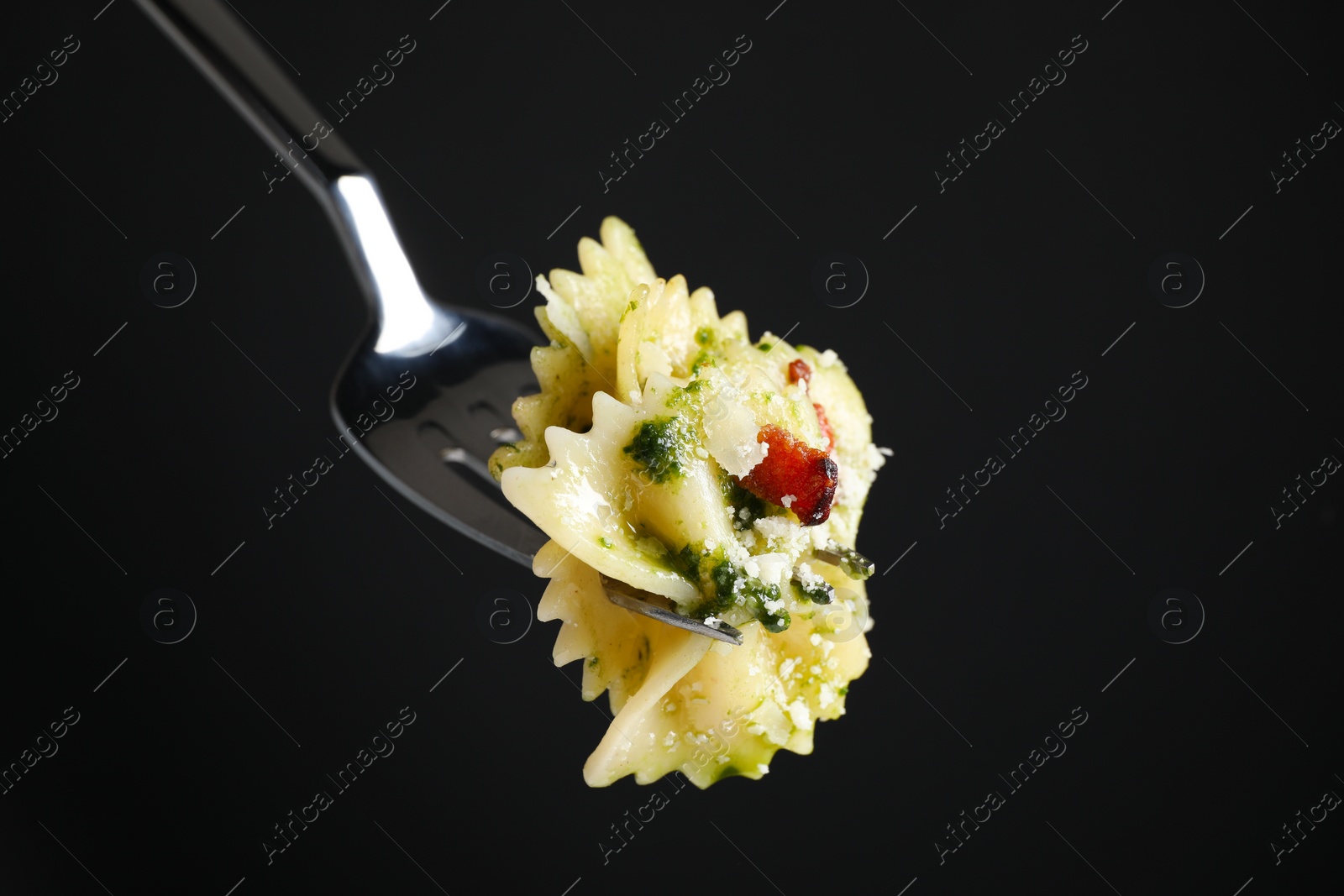 Photo of Fork with tasty pasta on black background, closeup