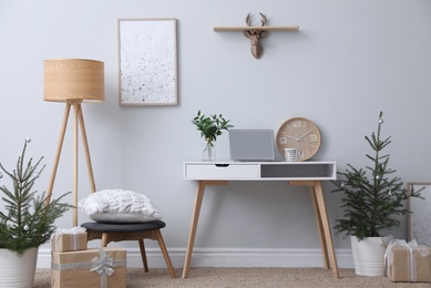 Stylish room interior with potted fir trees decorated for Christmas