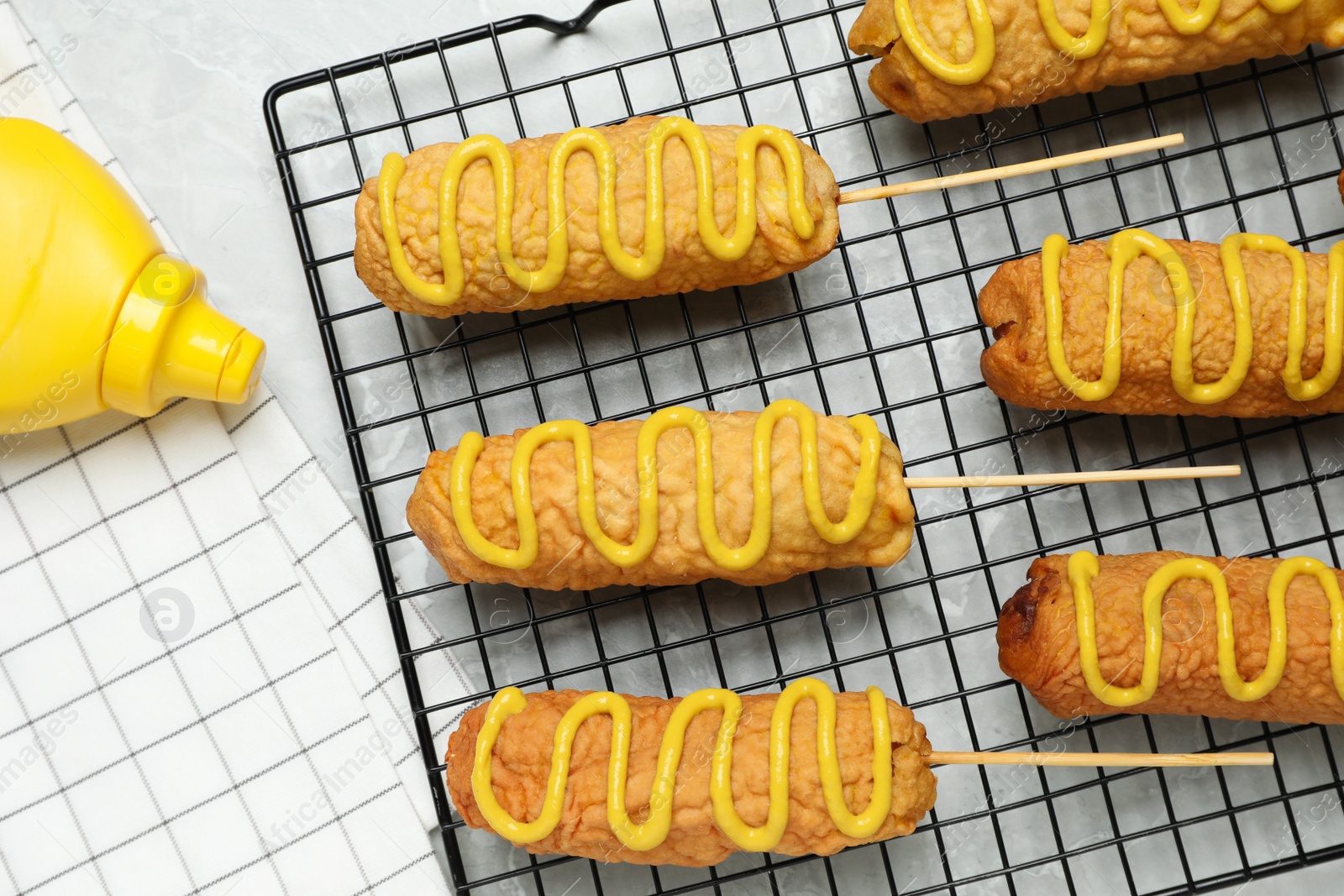 Photo of Delicious corn dogs with mustard on grey table, flat lay