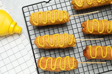 Delicious corn dogs with mustard on grey table, flat lay