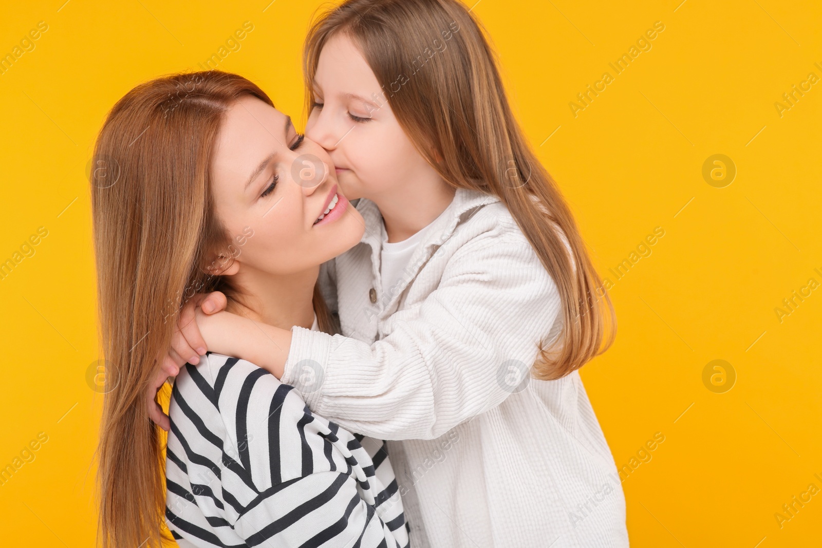 Photo of Portrait of mother and her cute daughter on orange background