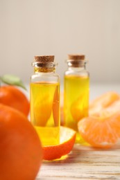 Bottles of tangerine essential oil, fresh fruits and peel on white wooden table
