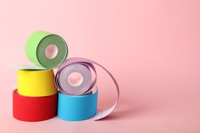 Photo of Bright kinesio tape in rolls on pink background. Space for text