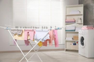 Clean laundry hanging on drying rack indoors