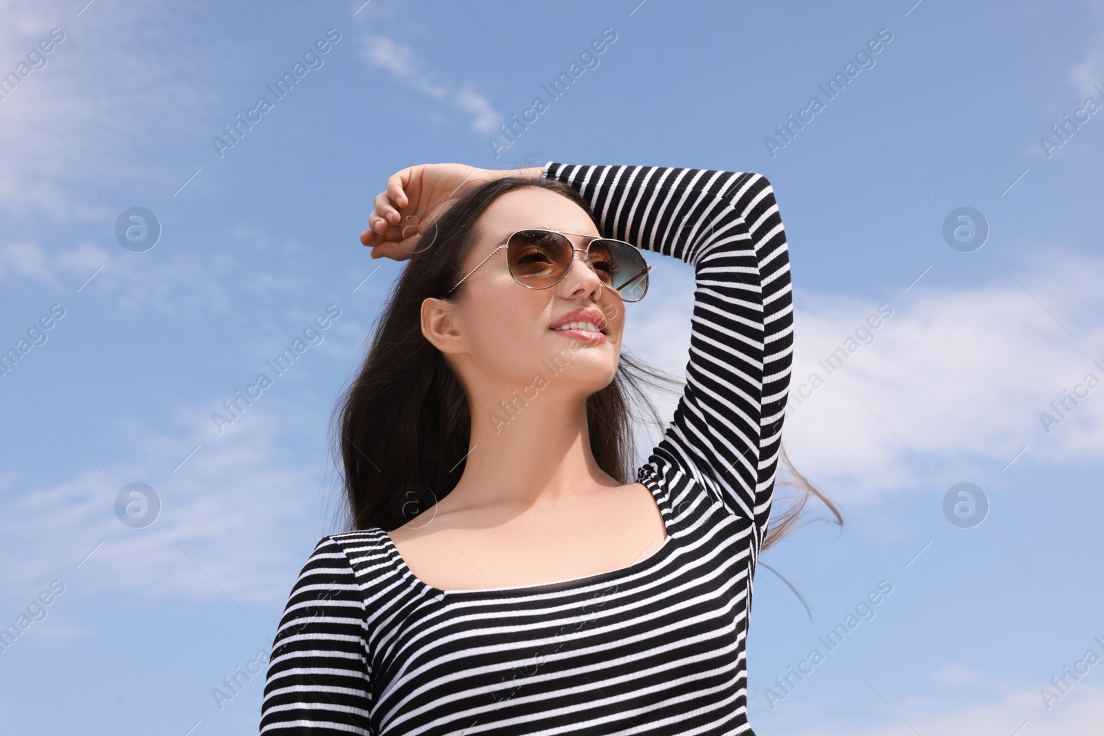 Photo of Beautiful smiling woman wearing stylish sunglasses outdoors