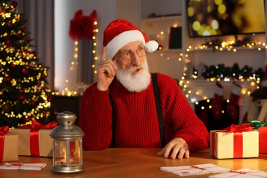 Emotional Santa Claus at his workplace in room decorated for Christmas