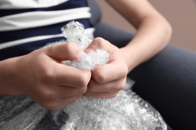 Boy popping bubble wrap, closeup. Stress relief