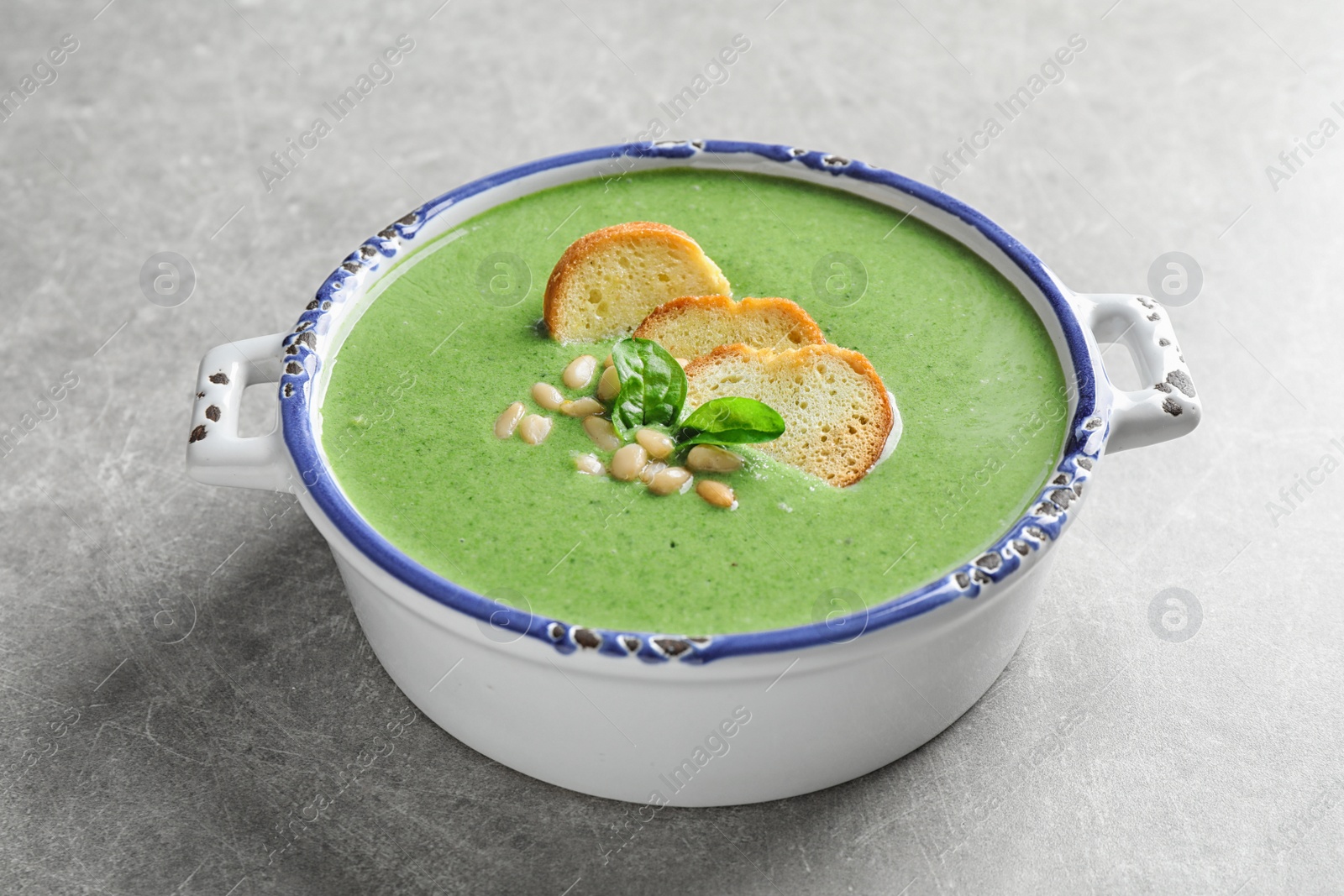 Photo of Bowl of healthy green soup with fresh spinach on light table