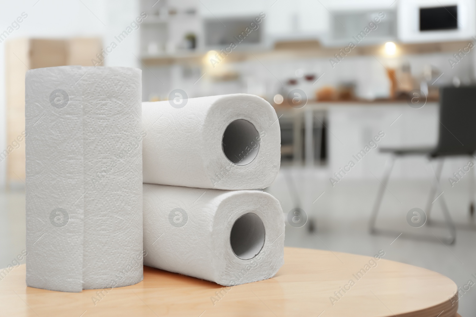 Photo of Rolls of paper towels on table in kitchen, space for text