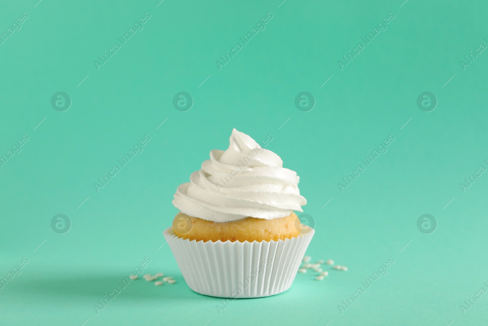 Photo of Delicious cupcake with white cream on turquoise background