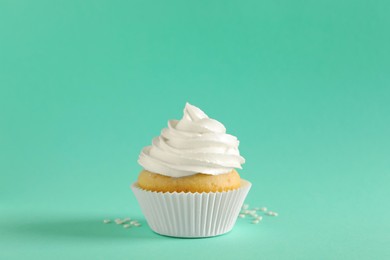 Delicious cupcake with white cream on turquoise background