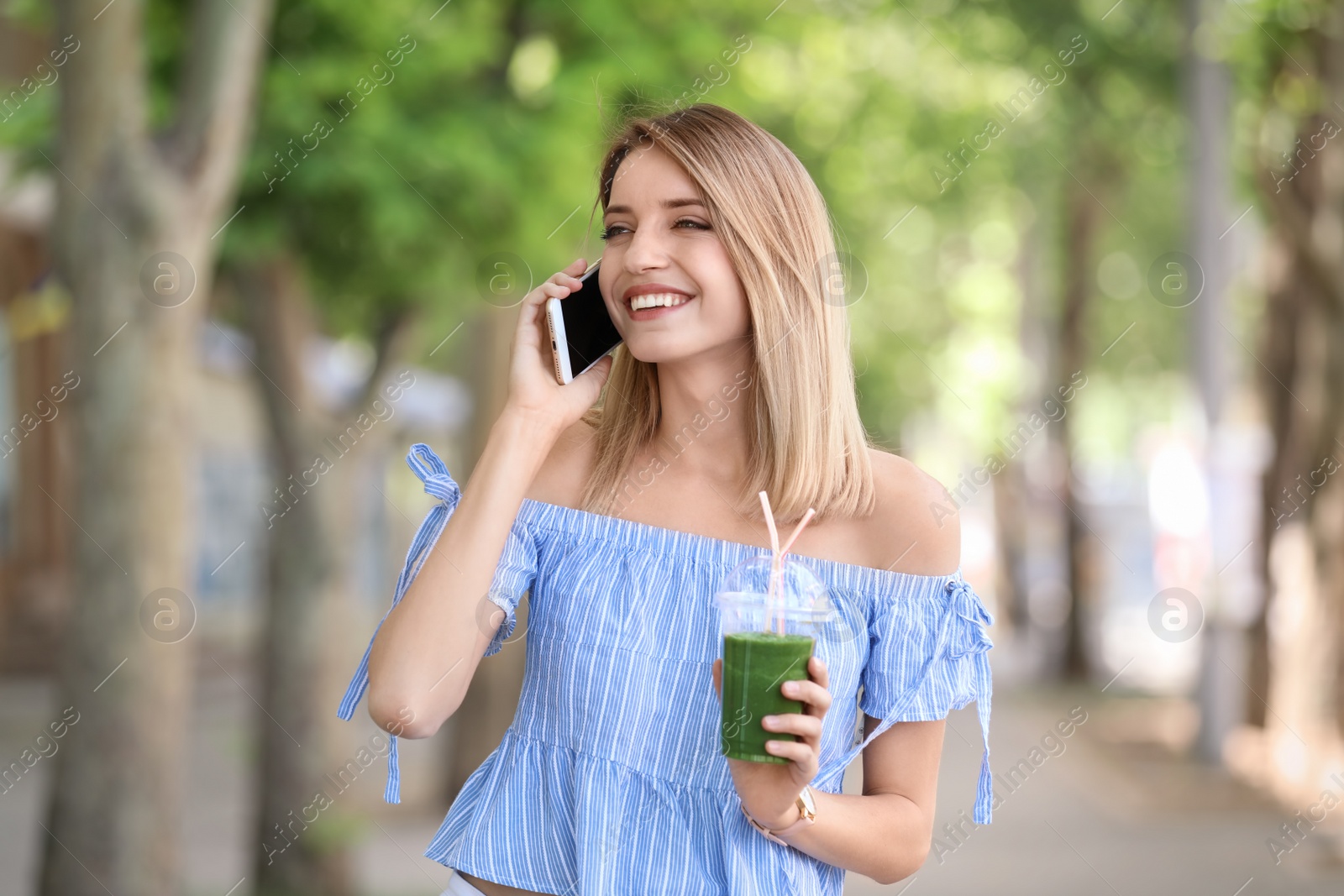 Photo of Young woman with plastic cup of healthy smoothie outdoors