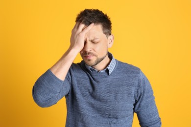 Photo of Man suffering from terrible migraine on yellow background