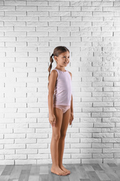 Photo of Cute little girl in underwear near white brick wall