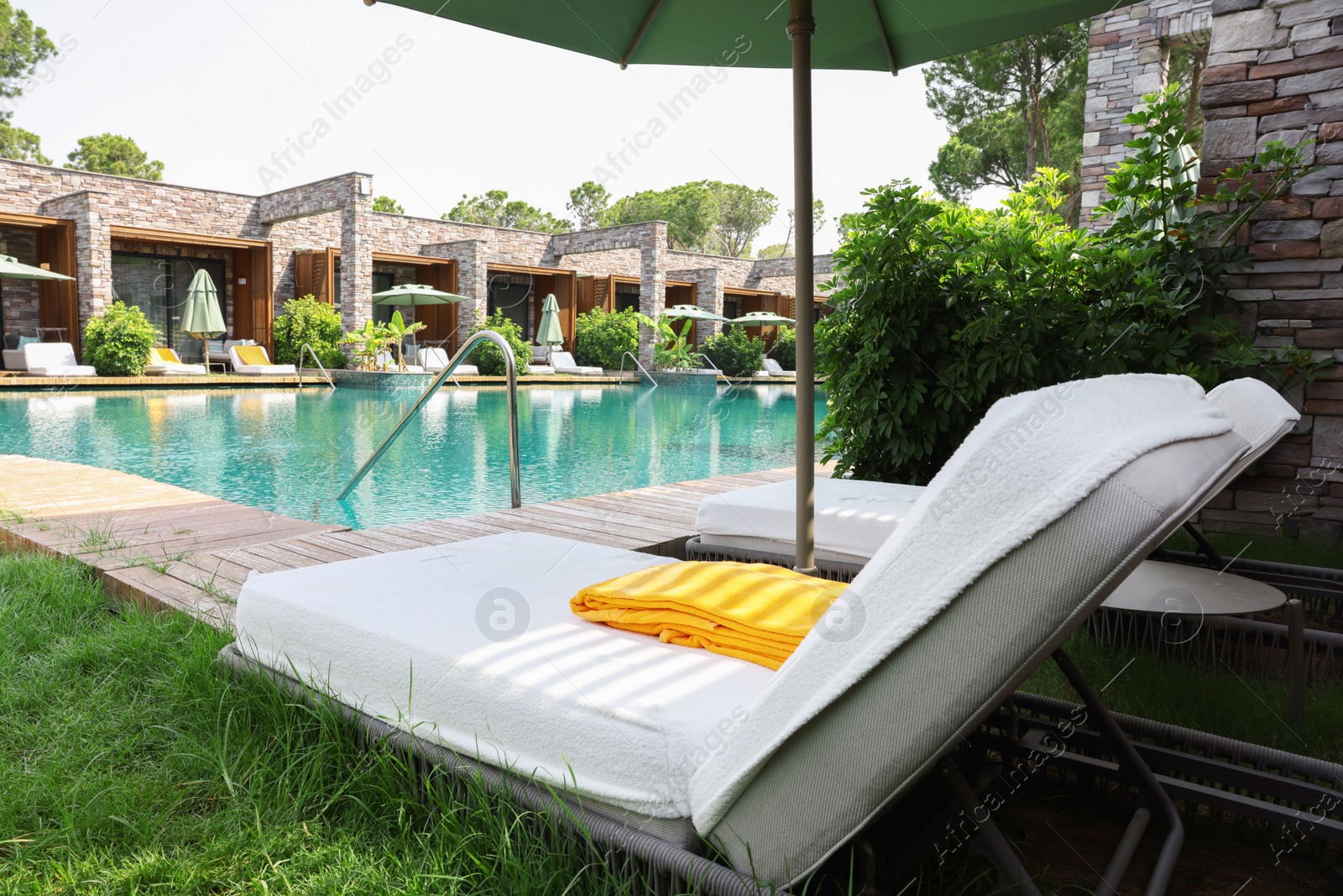 Photo of Sunbeds near outdoor swimming pool at luxury resort