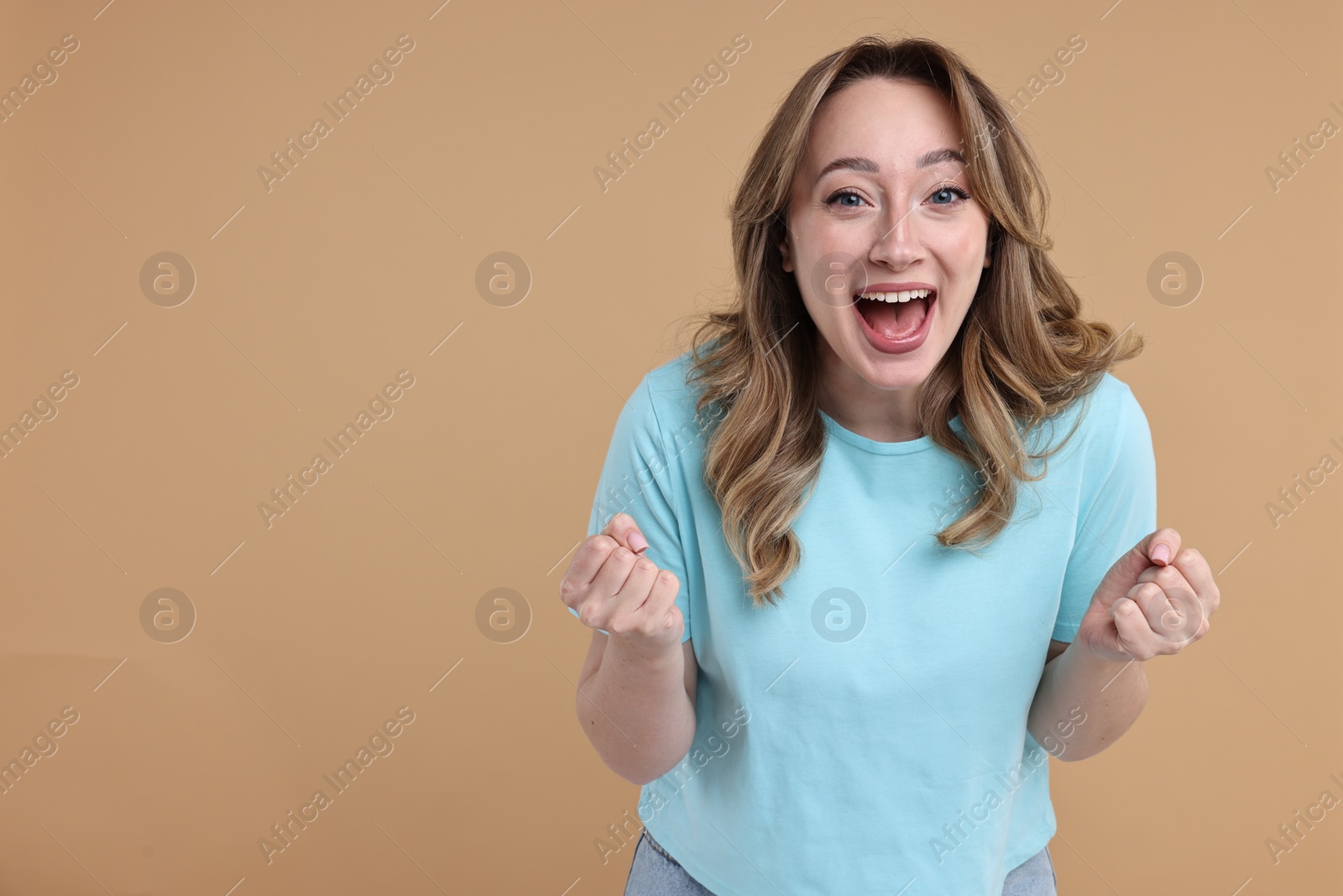 Photo of Portrait of happy surprised woman on beige background. Space for text