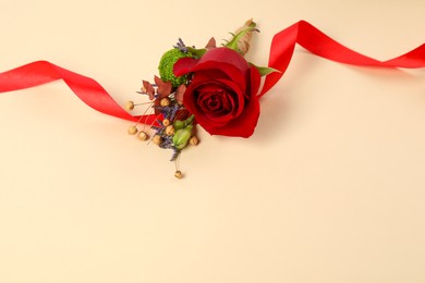 Photo of Stylish boutonniere with red rose and ribbon on beige background. Space for text