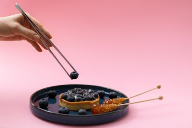 Food stylist creating beautiful composition with delicious dessert on pink background, closeup