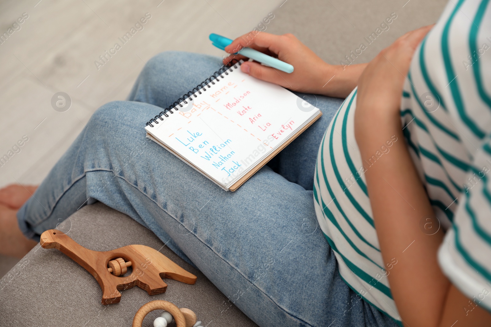 Photo of Pregnant woman with baby names list sitting on sofa, closeup