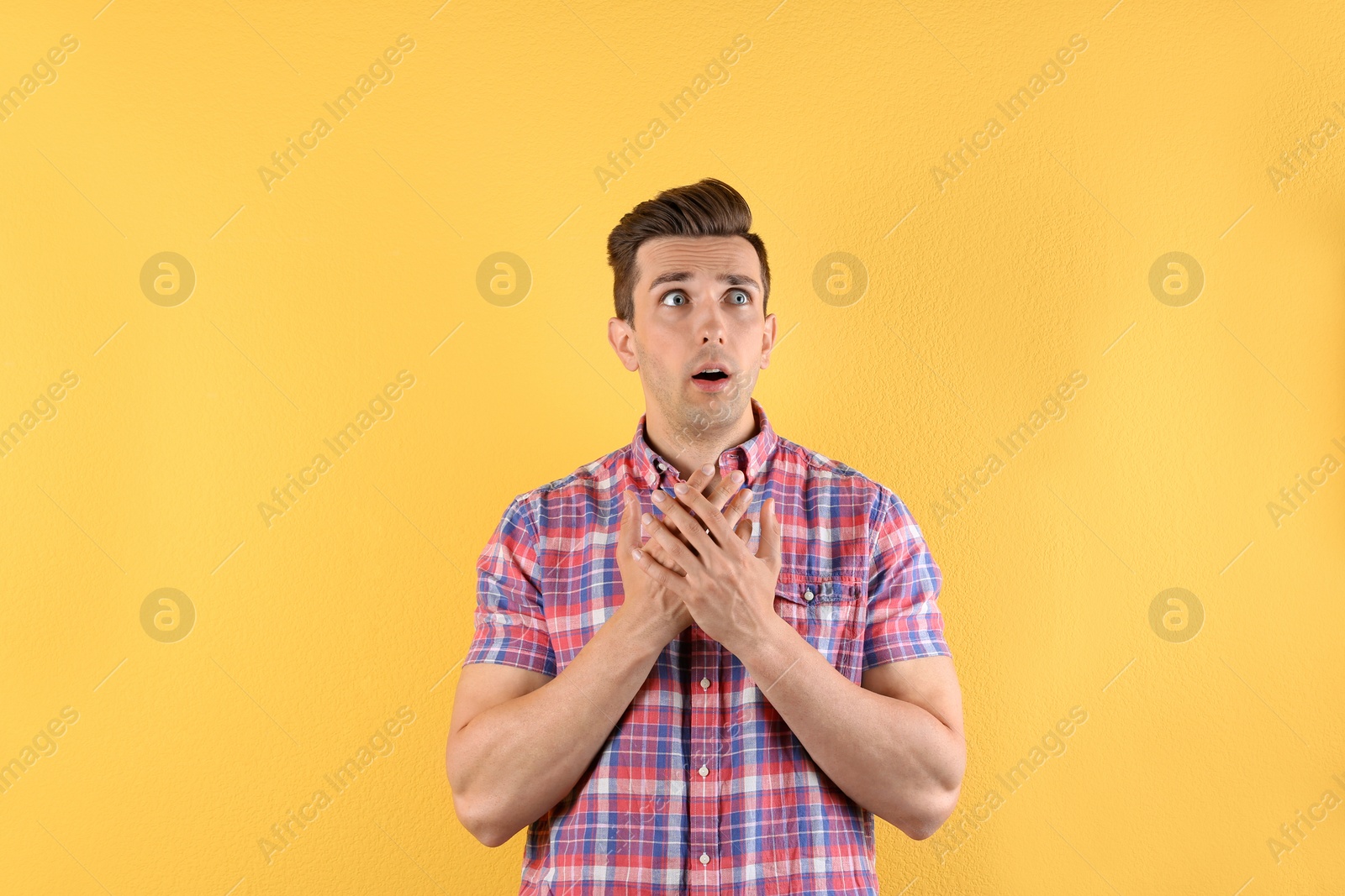 Photo of Handsome emotional young man on color background