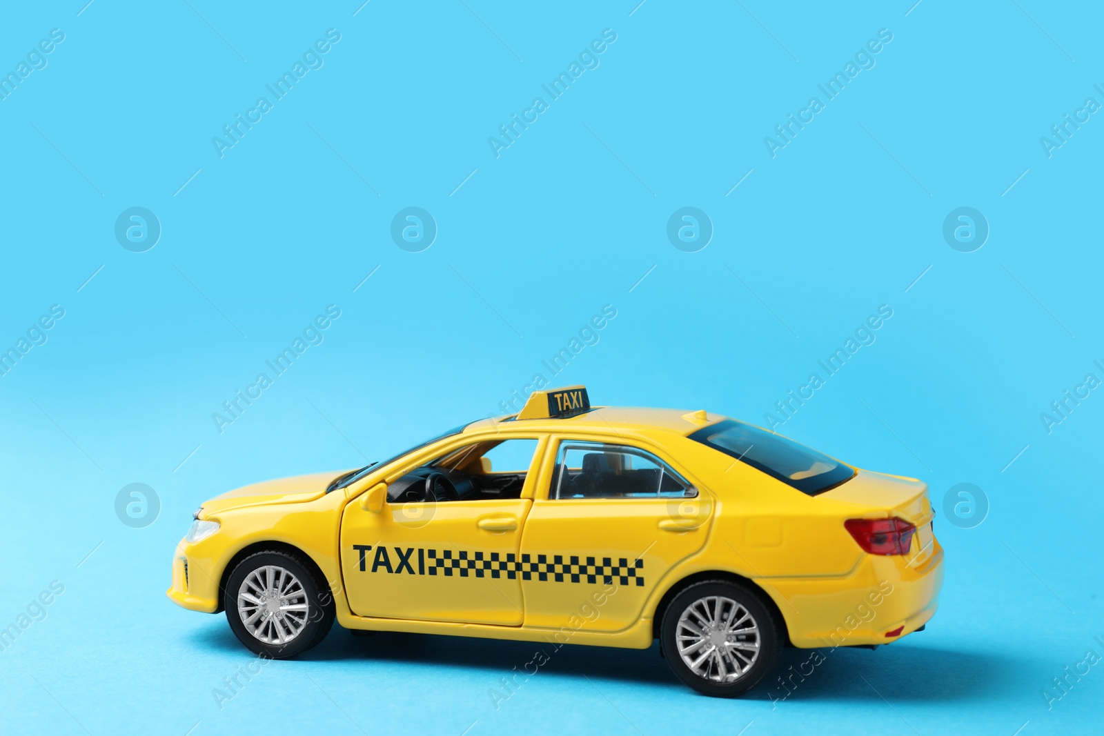 Photo of Yellow taxi car model on light blue background. Space for text