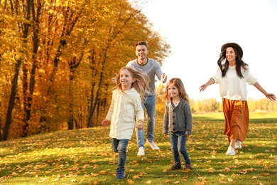Photo of Happy family with little daughters having fun in park. Autumn park