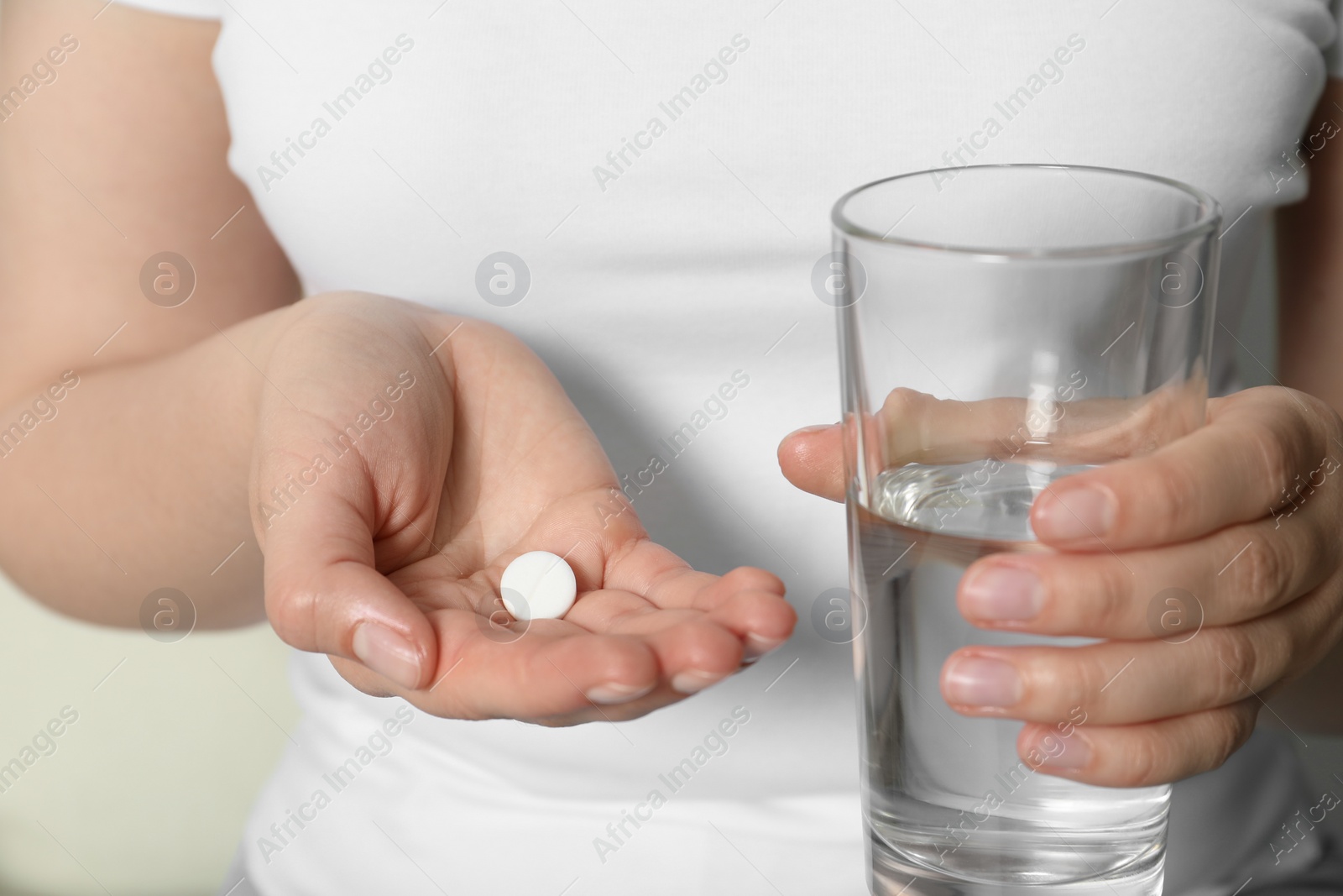 Photo of Woman holding glass of water and pill, closeup