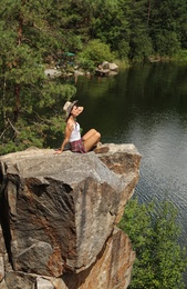 Young woman on rocky mountain near lake. Camping season