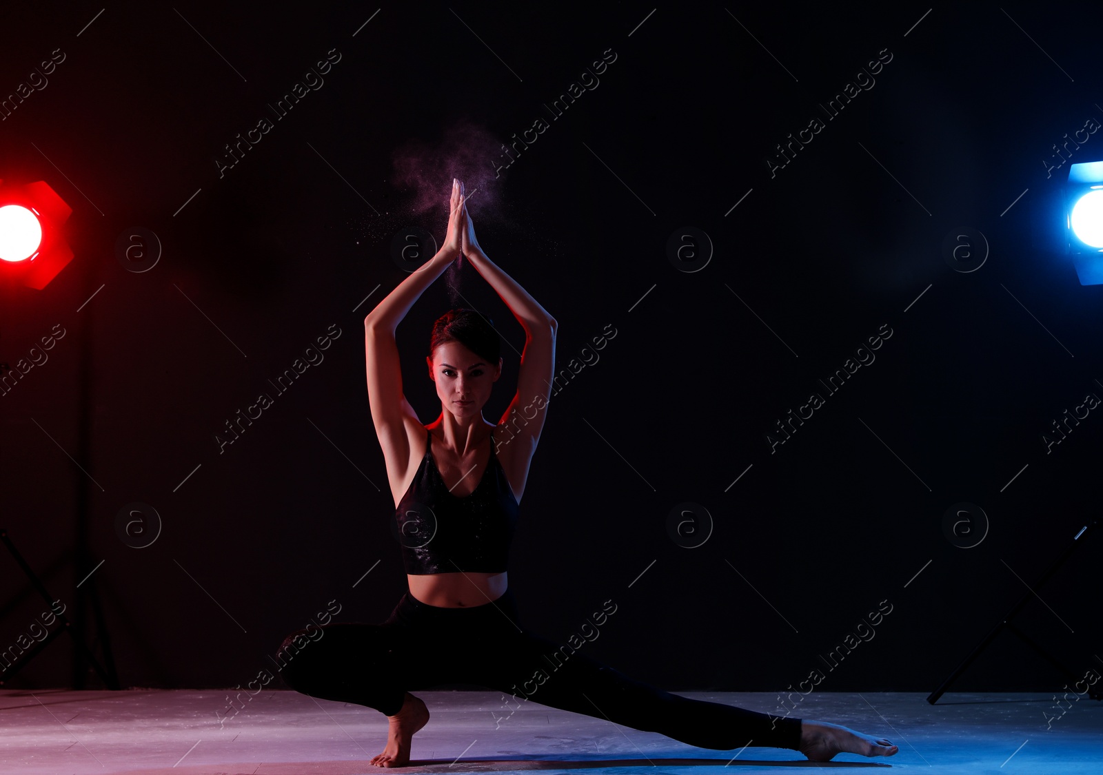 Photo of Professional acrobat with chalk powder exercising in dark studio