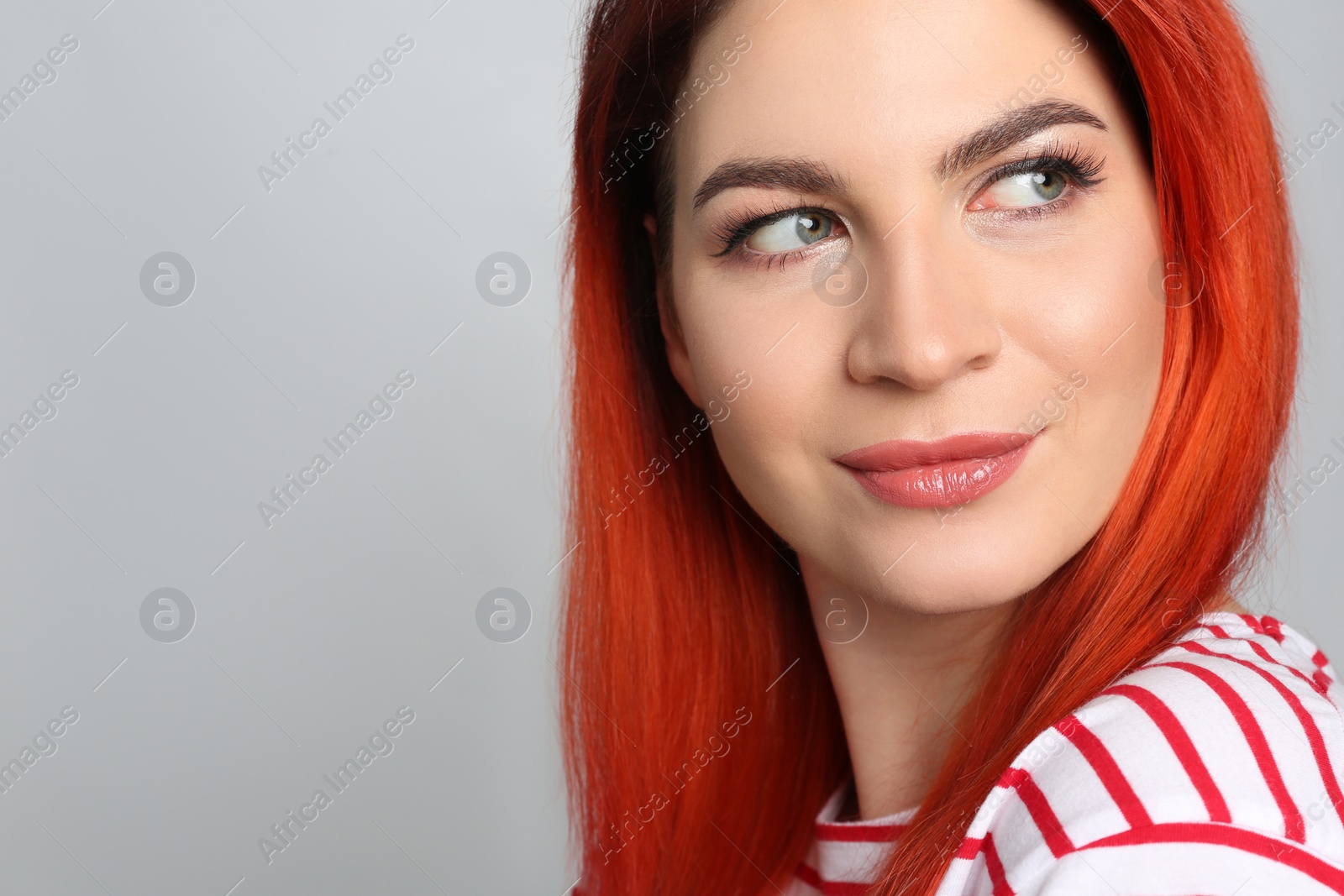 Photo of Young woman with bright dyed hair on grey background, closeup. Space for text