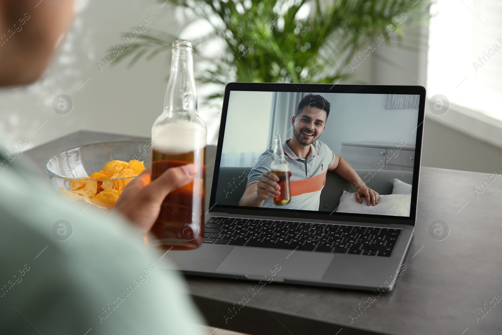 Photo of Friends drinking beer while communicating through online video conference at home. Social distancing during coronavirus pandemic