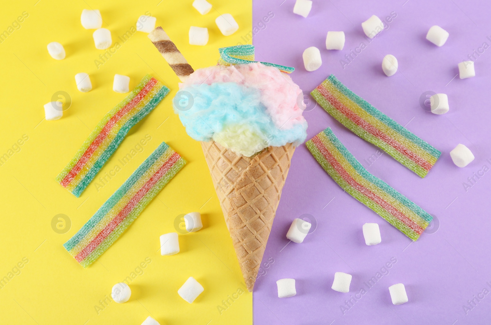 Photo of Sweet cotton candy in waffle cone and marshmallows on color background, flat lay