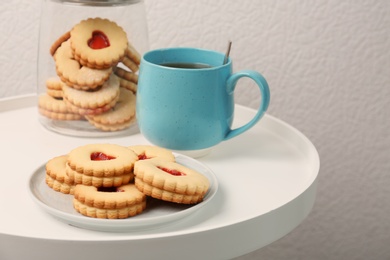 Photo of Traditional Christmas Linzer cookies with sweet jam and cup of tea on table