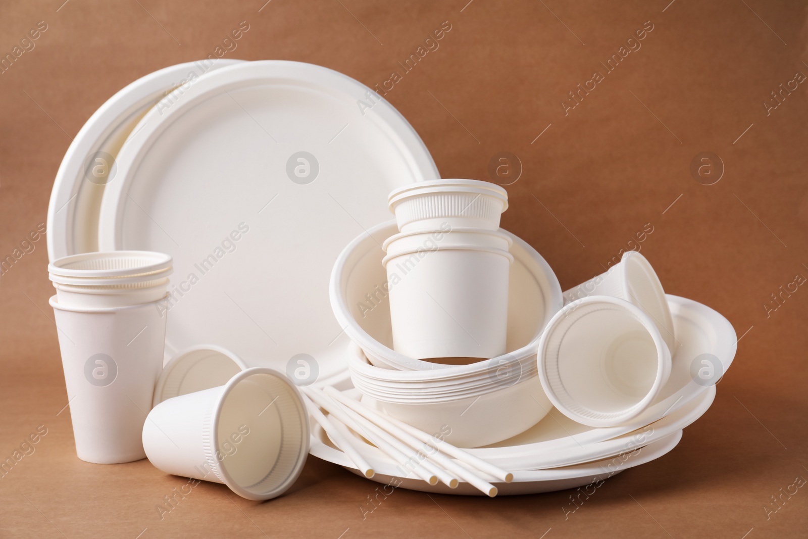 Photo of Set of disposable tableware on brown background