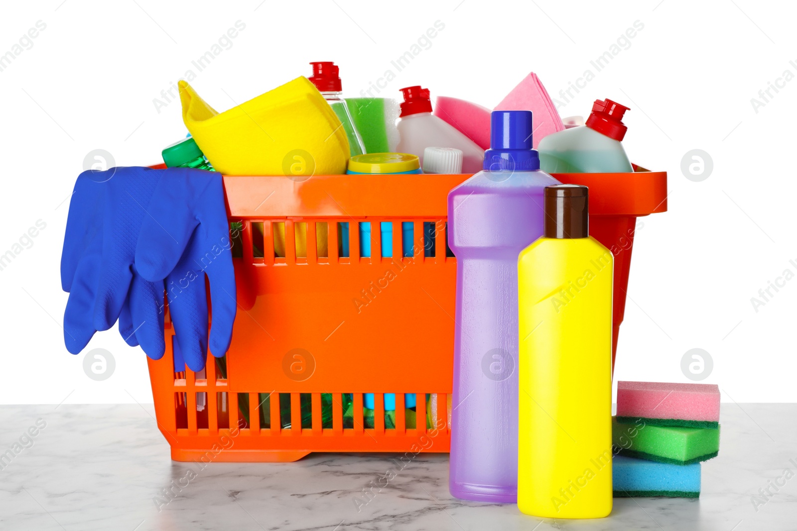 Photo of Shopping basket with different detergents on marble table against white background