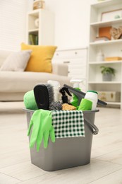 Photo of Different cleaning supplies in bucket on floor at home