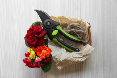 Photo of Secateur, beautiful roses and rope on white wooden table, top view