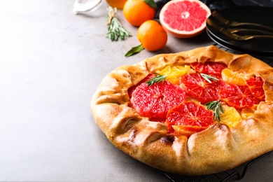 Tasty galette with citrus fruits and rosemary on light grey table. Space for text