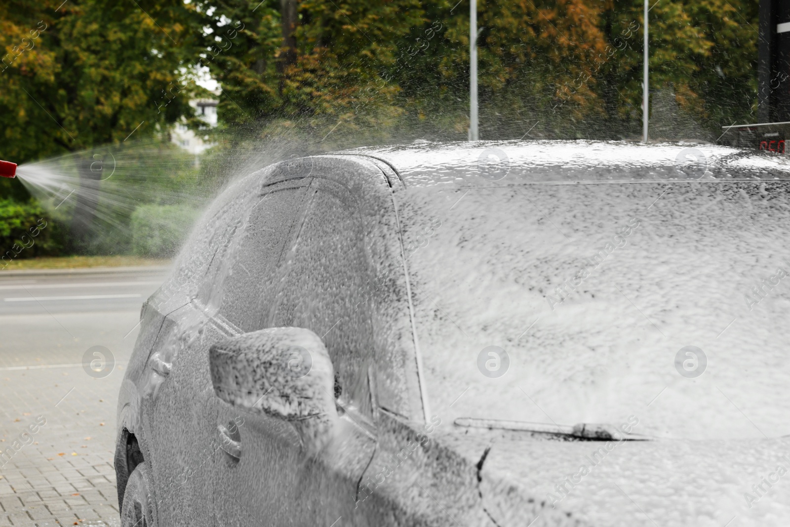 Photo of Washing auto with high pressure water jet at outdoor car wash, closeup