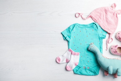 Flat lay composition with cute clothes and space for text on white wooden background. Baby accessories