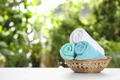 Photo of Basket with soft bath towels on table against blurred background. Space for text