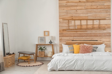 Photo of Stylish room interior with comfortable bed near wooden wall